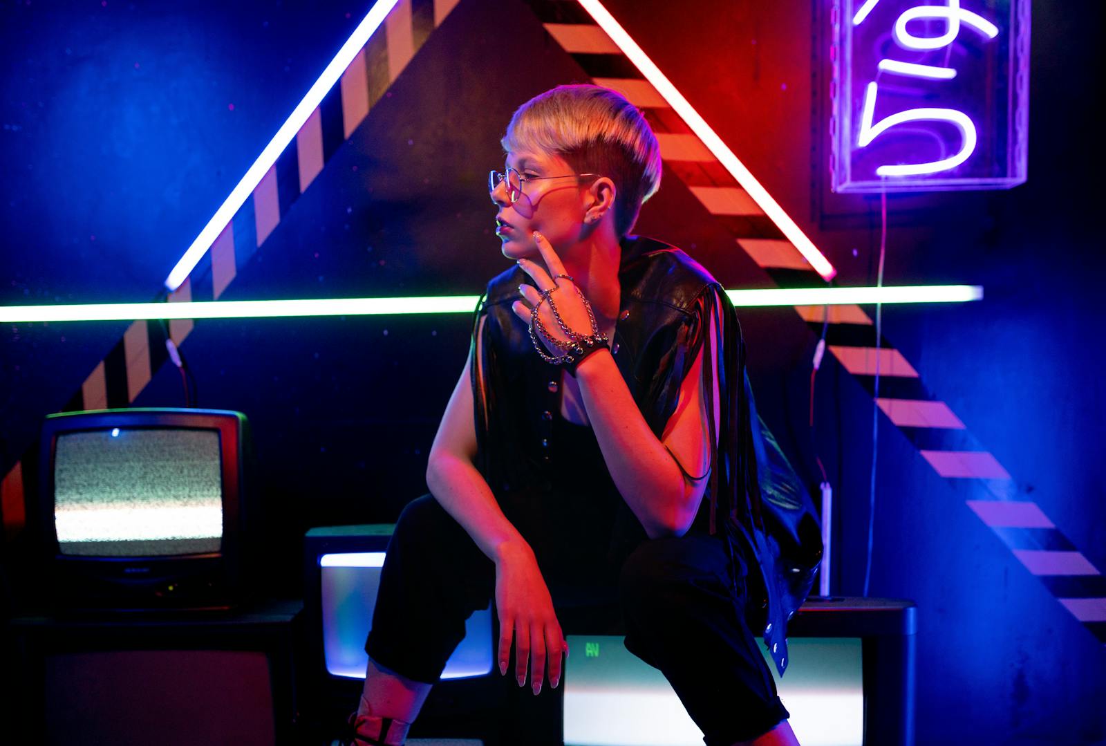 Person in modern fashion in a neon-lit retro room with vintage TVs.