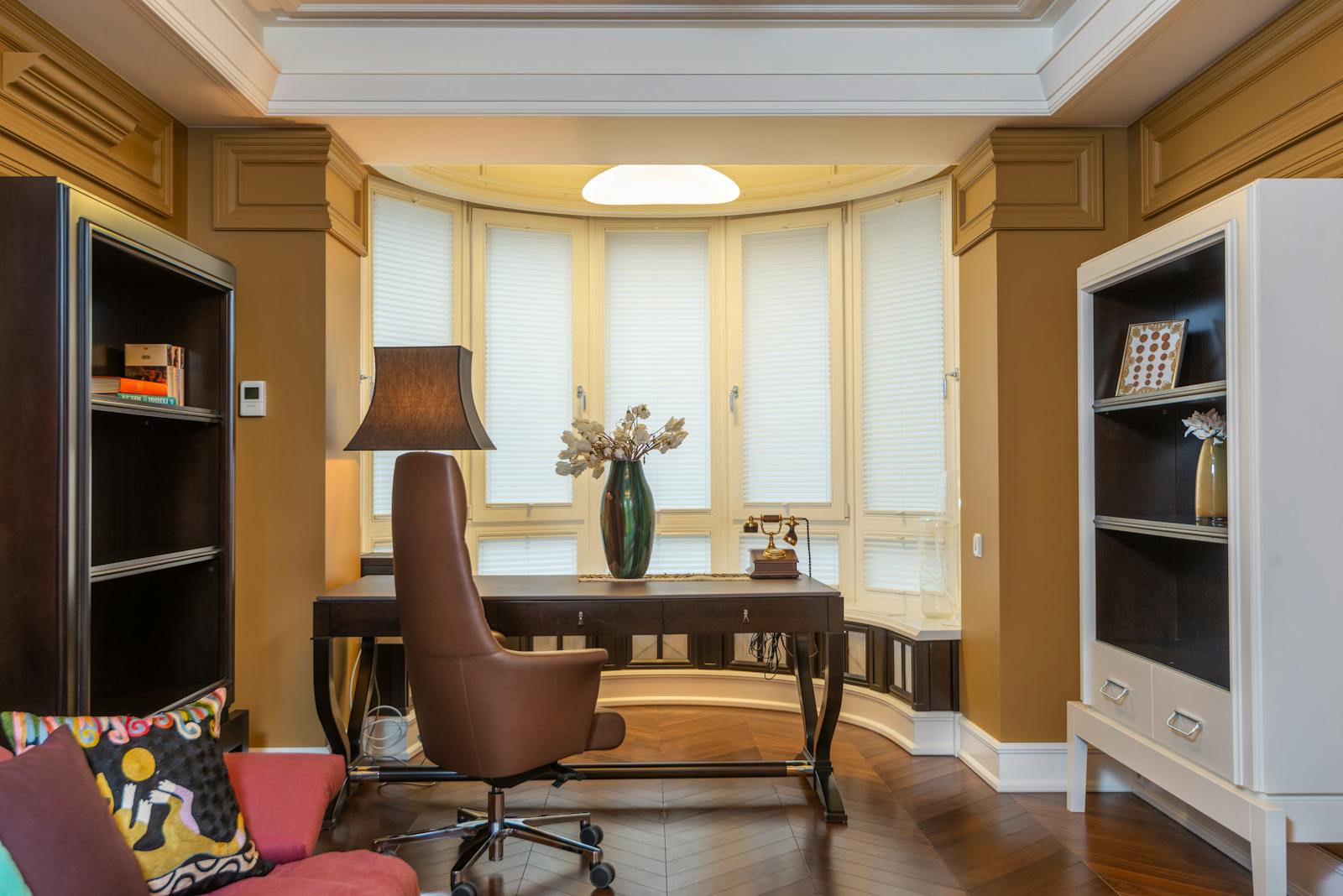 Stylish home office featuring a comfortable armchair, desk, bookshelves, and decorative elements.