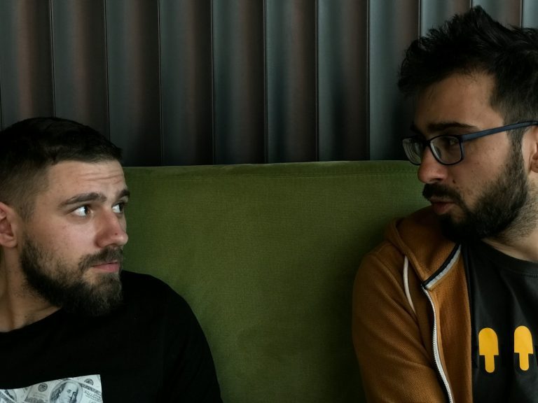 a couple of men sitting on top of a green couch
