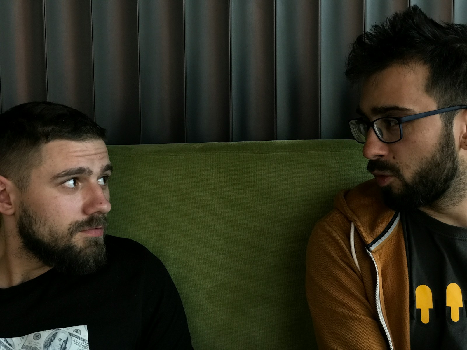 a couple of men sitting on top of a green couch