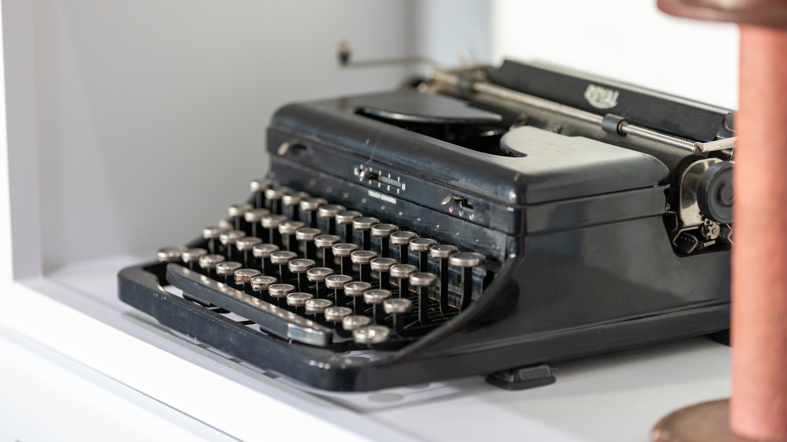 black typewriter beside wall