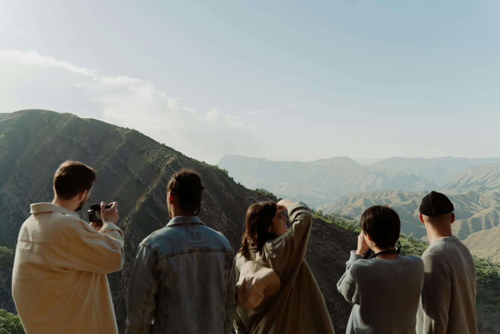 A group of friends observing a scenic mountain view on a sunny day.