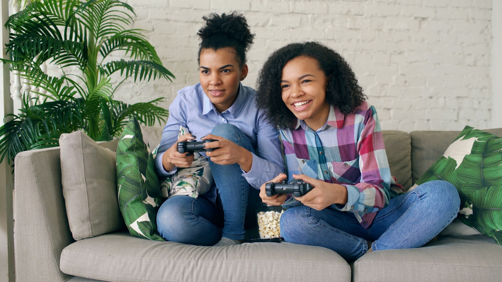 Two women playing video games on a couch.