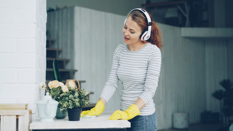 Woman with headphones cleaning and singing