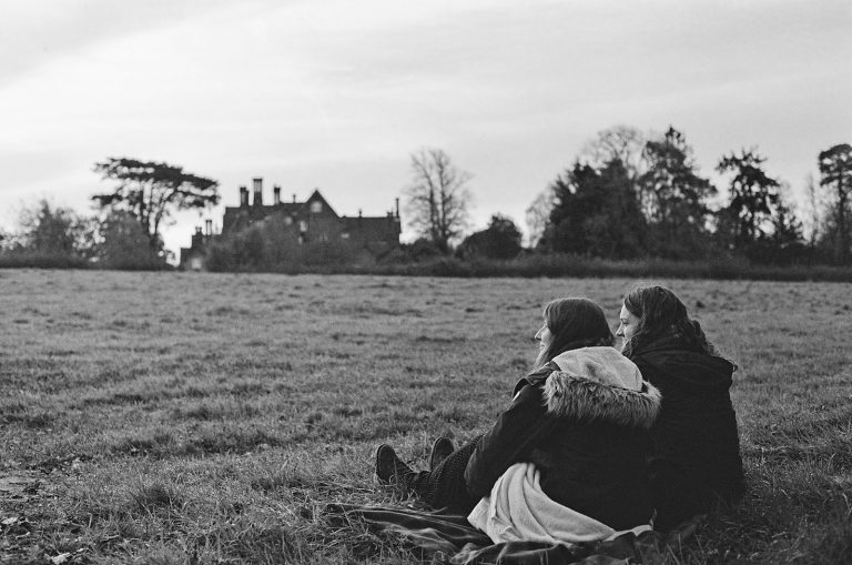 a couple of people sitting on top of a grass covered field