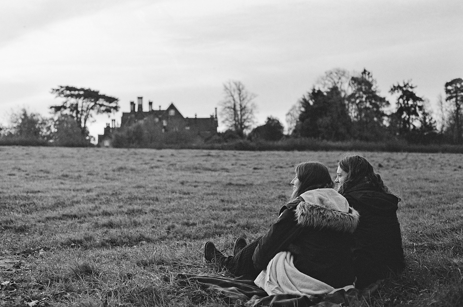 a couple of people sitting on top of a grass covered field