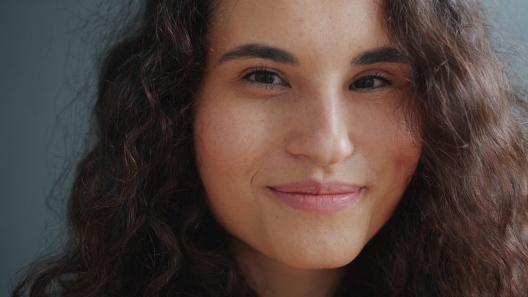 A young woman with curly hair smiles gently smiles.