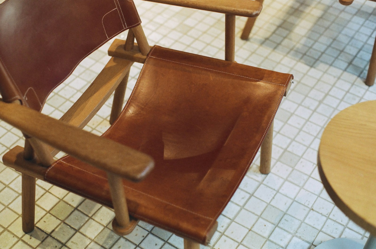 a brown leather chair sitting on top of a tiled floor
