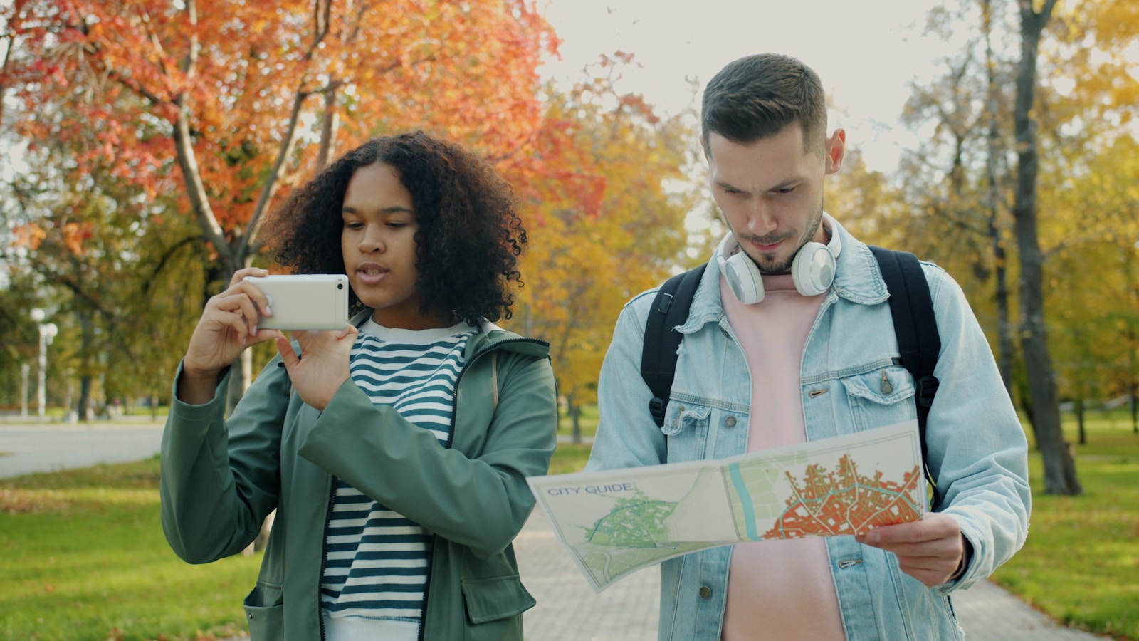 Couple looking at map and taking photo in park.