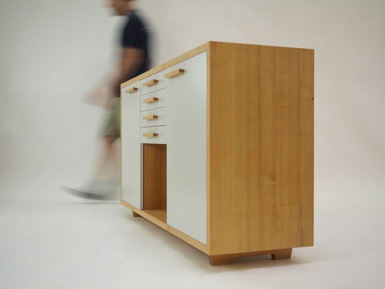 person walking beside white and brown wooden sideboard