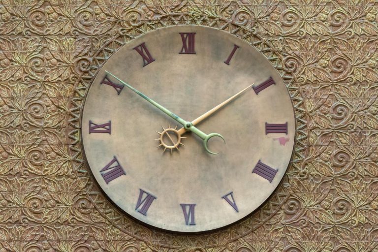A vintage-style wall clock set against a textured, ornate background with Roman numerals.