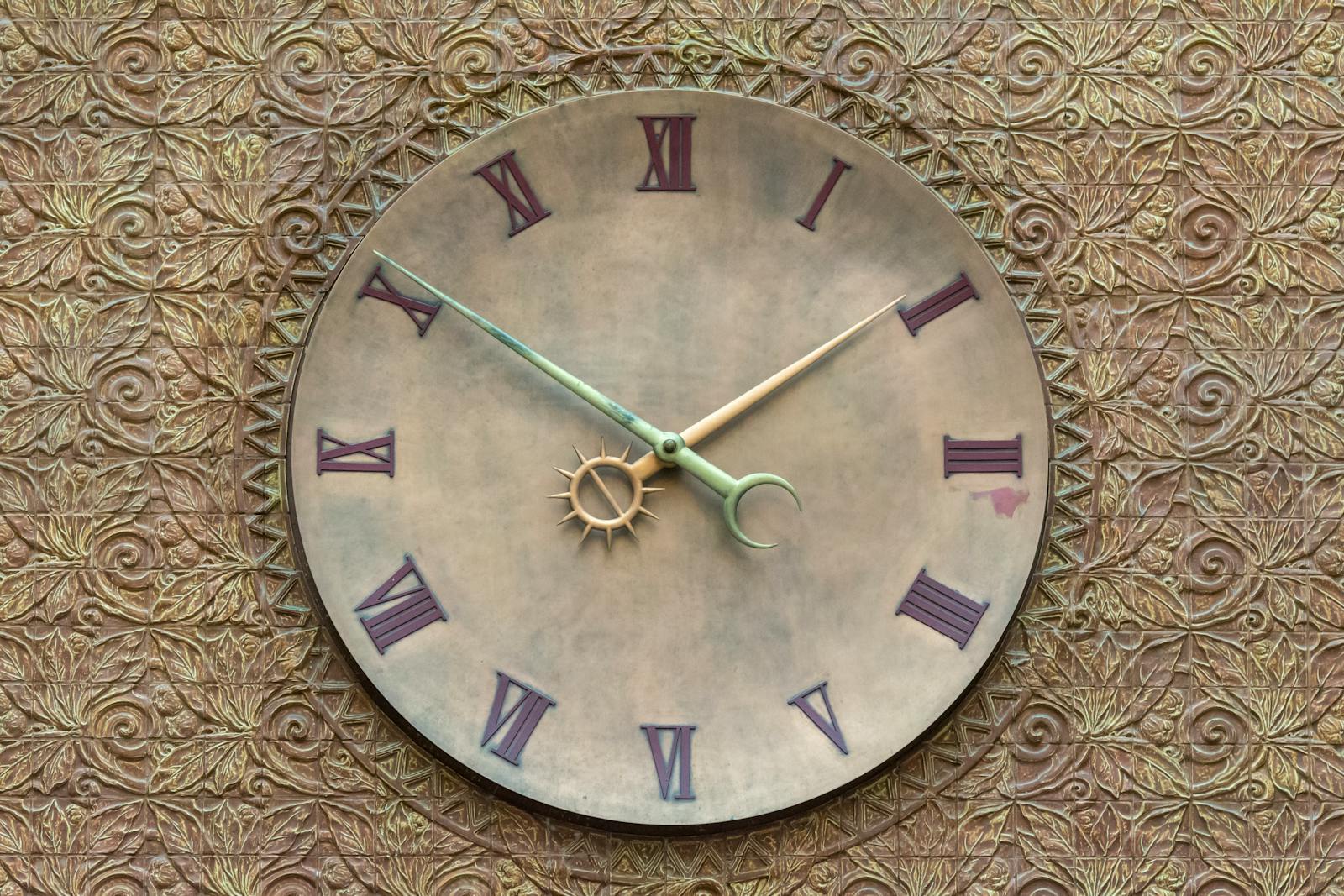 A vintage-style wall clock set against a textured, ornate background with Roman numerals.