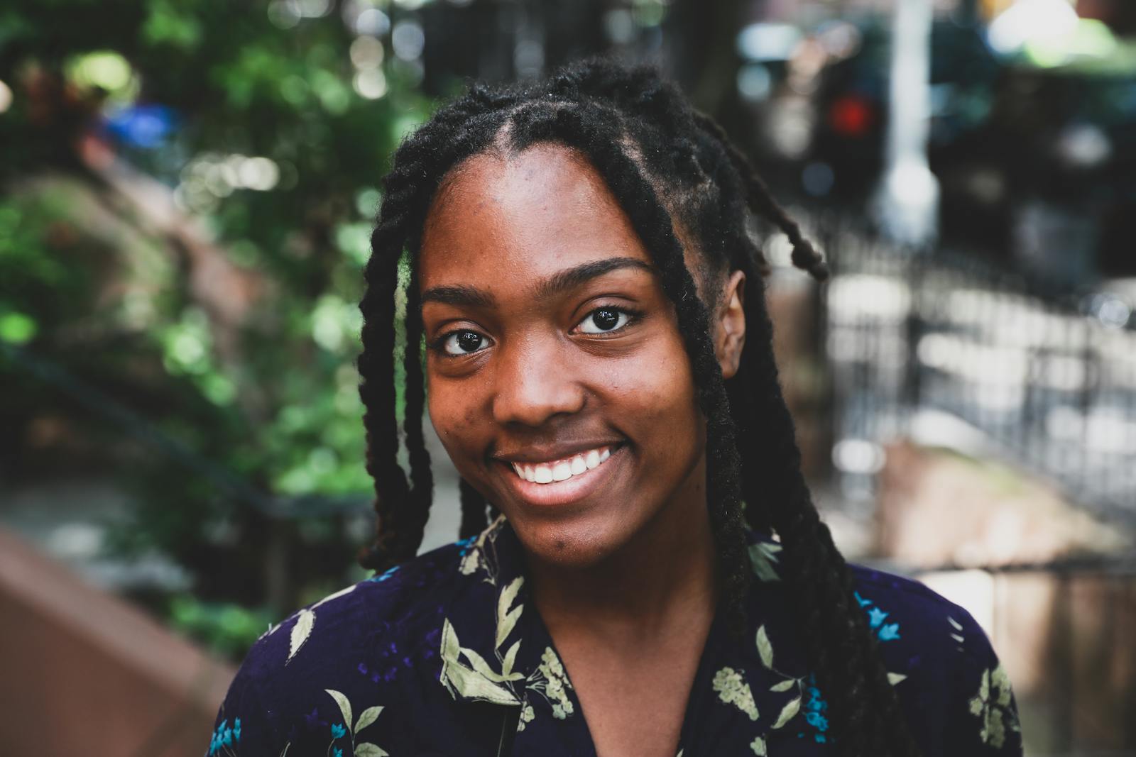 Portrait of a happy woman with braided hair smiling outdoors in a natural setting.