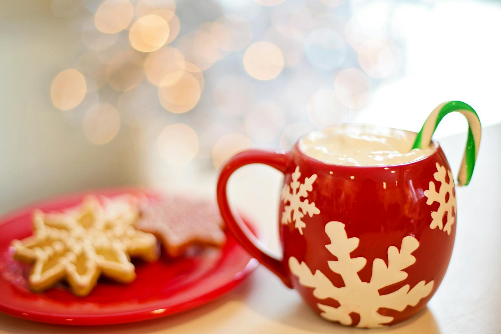 Warm holiday beverage with candy cane and cookies for a festive treat.