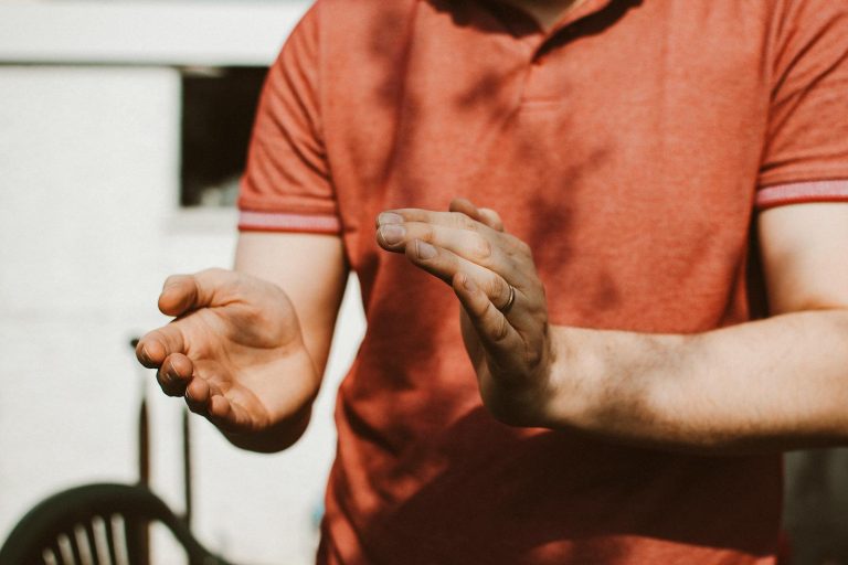 Hands clapping outdoors in warm sunlight, highlighting a ring on a finger
