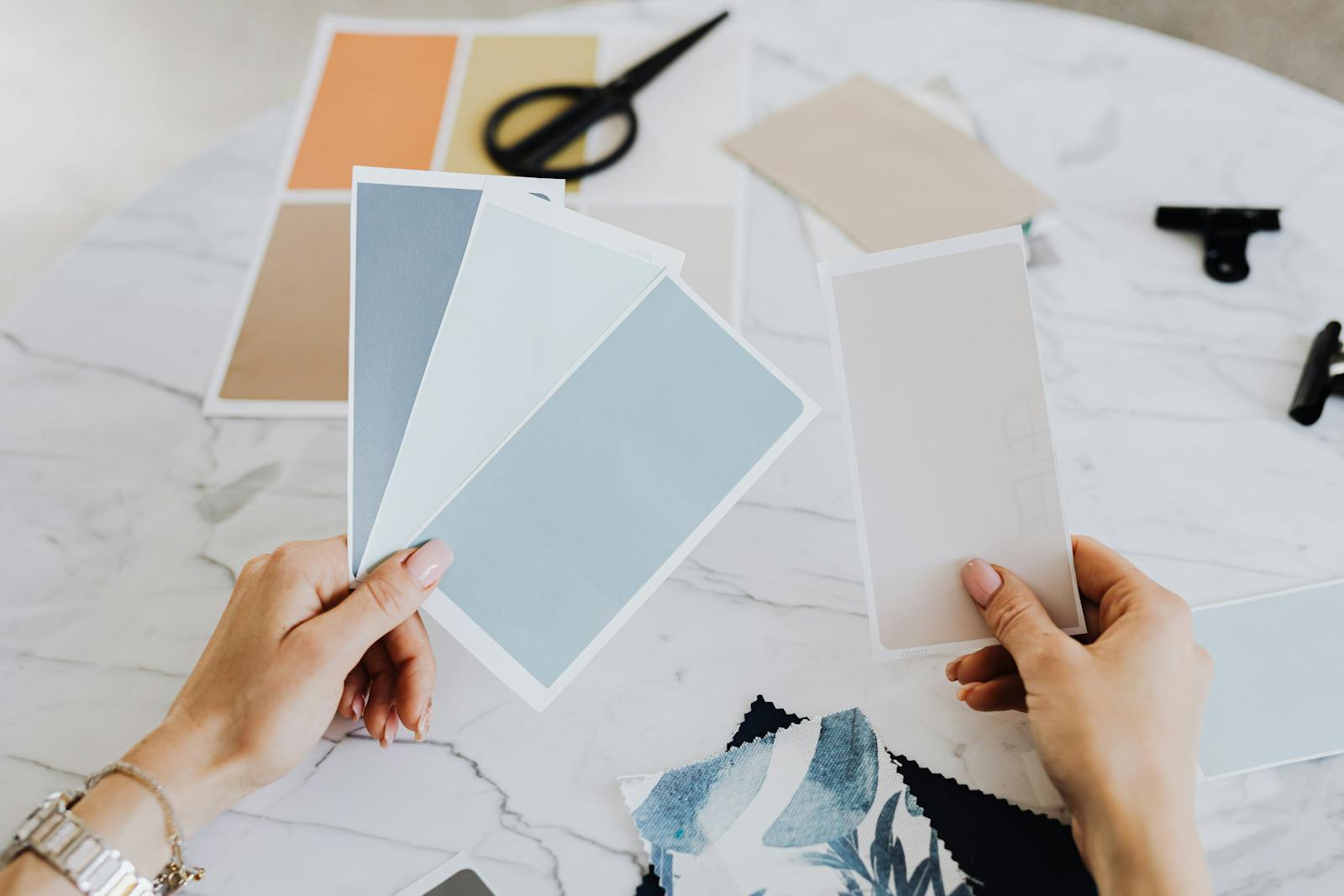 Hands holding color swatches and fabric samples for creative design projects.