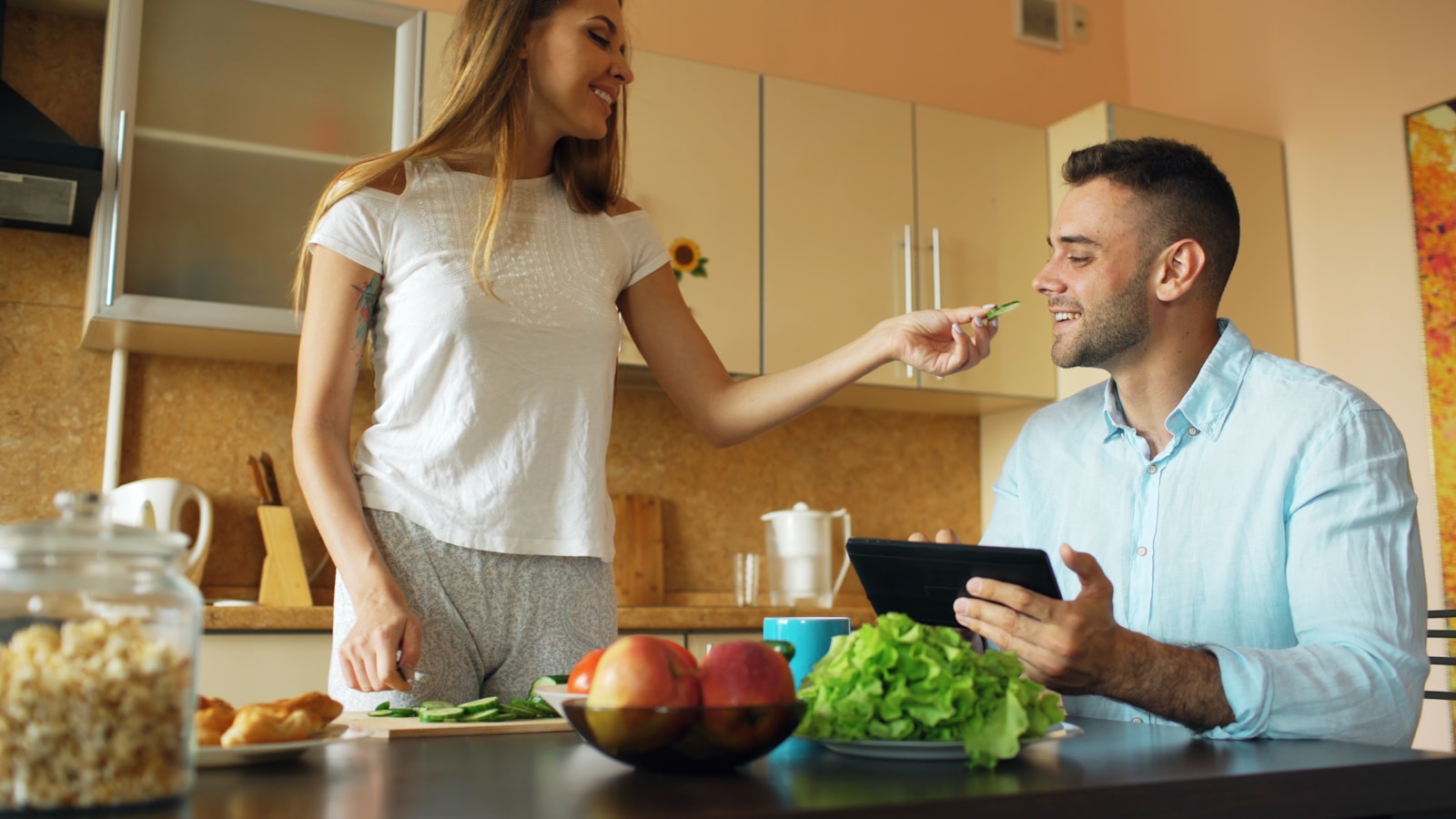 Couple smiling and talking in a kitchen.