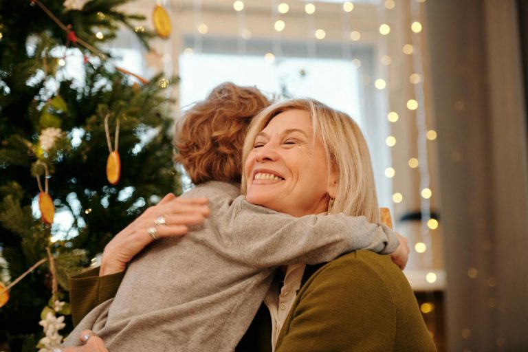 Loving embrace between a grandmother and grandson near a festive Christmas tree.