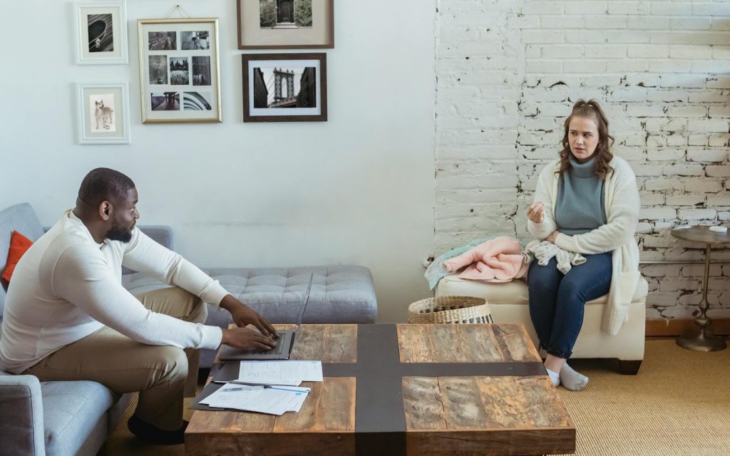 Full body of multiracial couple sitting in living room and sorting things out