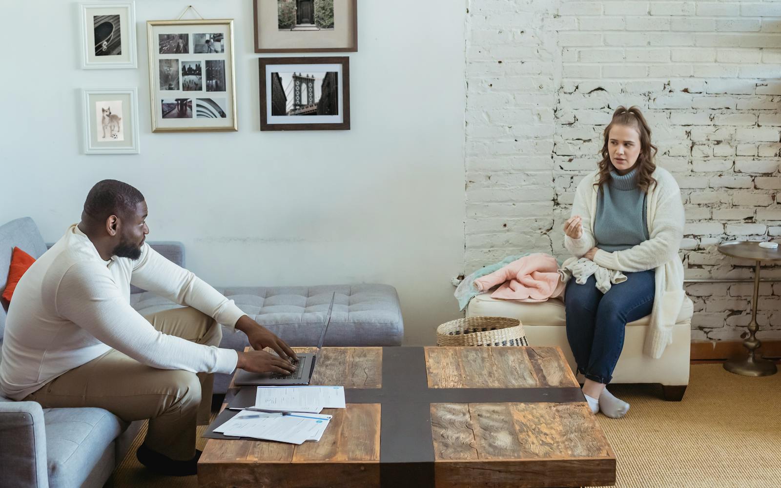 Full body of multiracial couple sitting in living room and sorting things out
