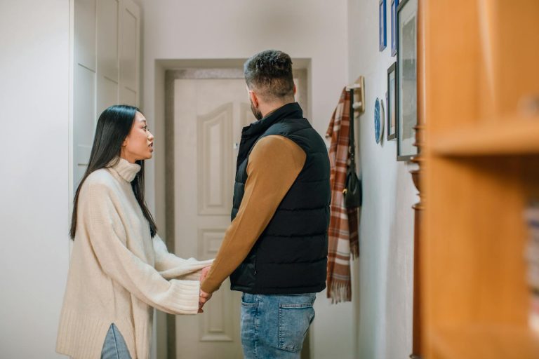 A couple engages in a serious conversation, holding hands inside a cozy home.