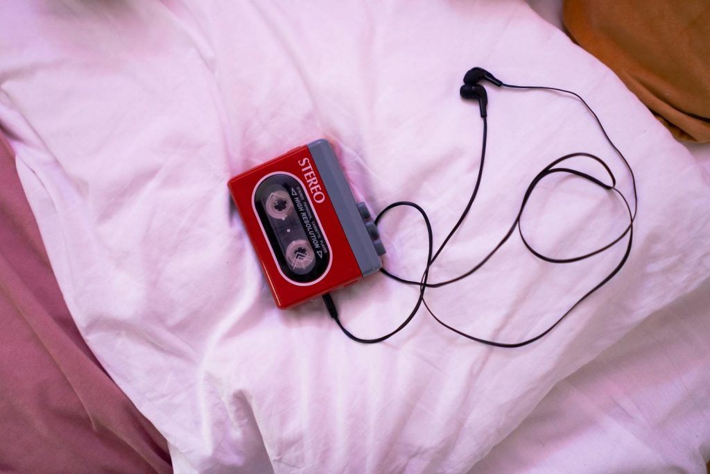 Retro cassette player and earphones elegantly placed on a bed, capturing a nostalgic vibe.