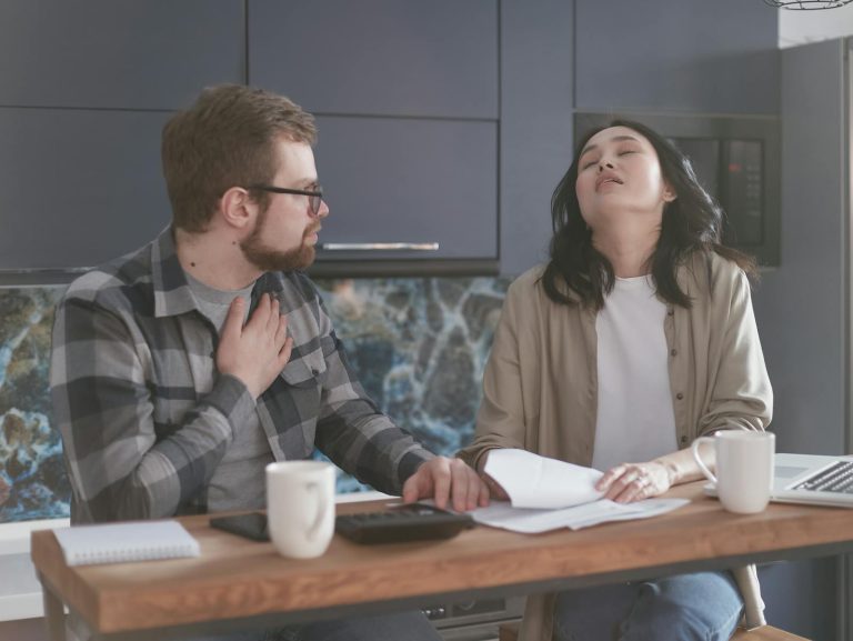 A couple experiencing stress while discussing finances in a modern kitchen setting.