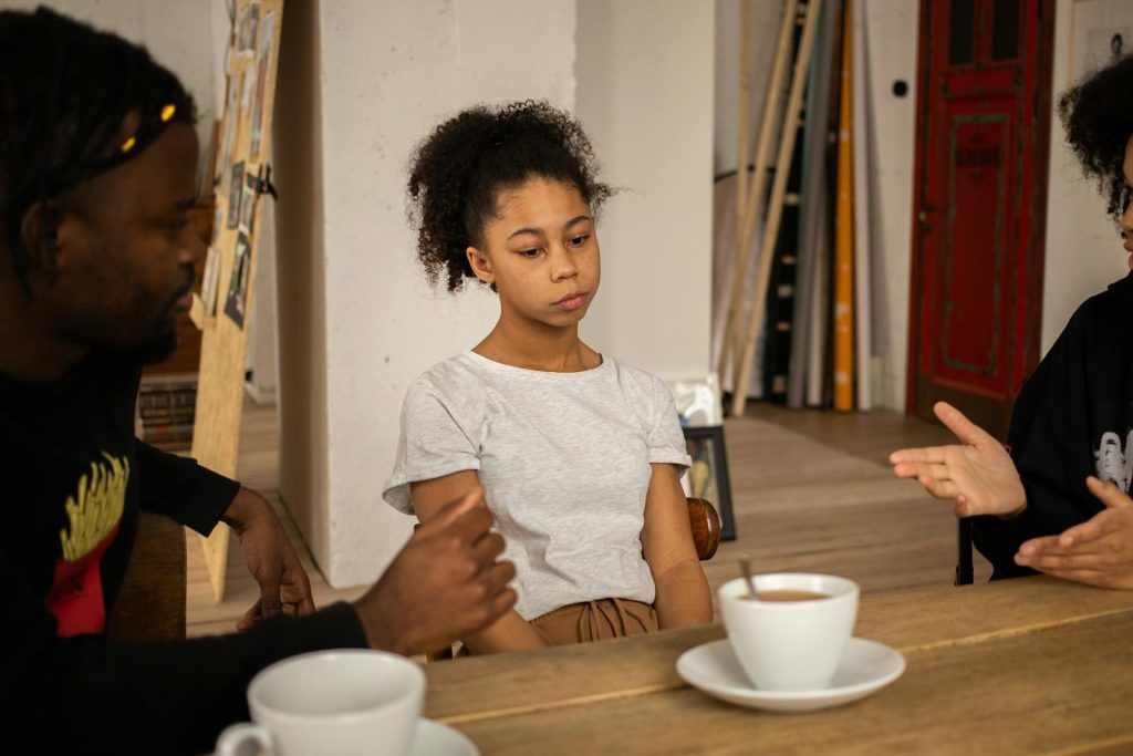 A family having a serious conversation at a table with coffee cups, highlighting a tense atmosphere indoors.