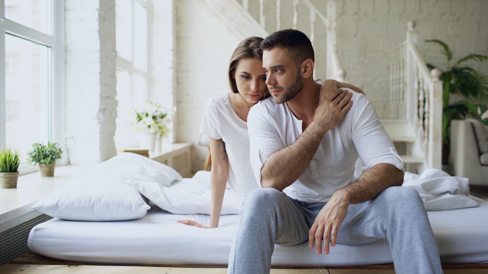 Couple sitting on a bed in a bright room