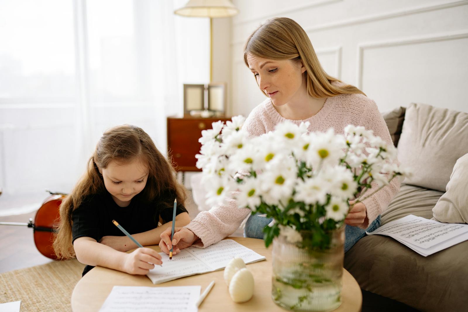 A mother helping her daughter read music notes at home, fostering education and creativity.