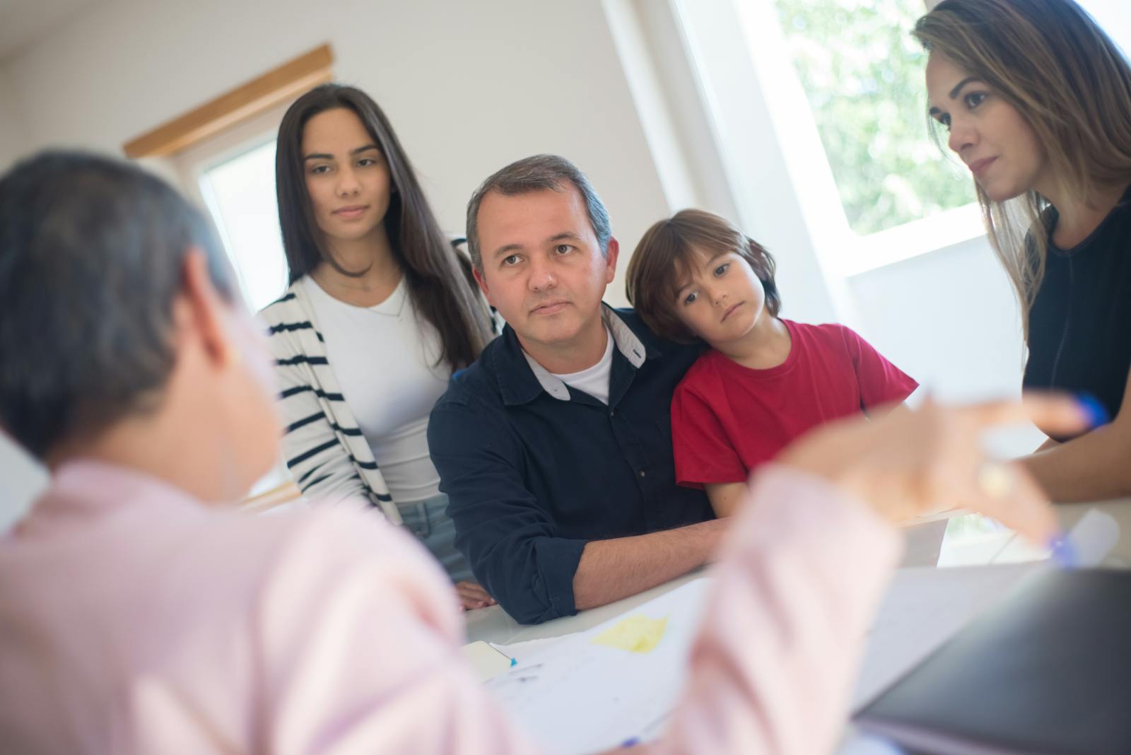A family of four seeks advice from a professional during an indoor consultation in a bright room.