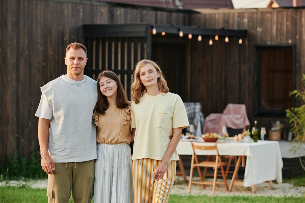 Smiling family standing in backyard with table setup for outdoor gathering.