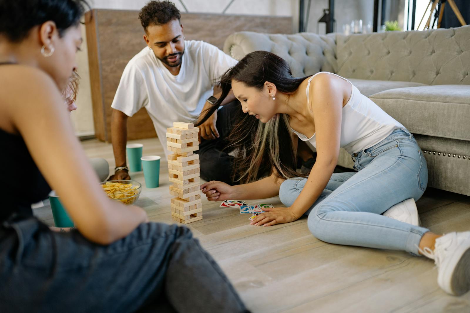 A group of friends playing Jenga on the living room floor, sharing a joyful moment.