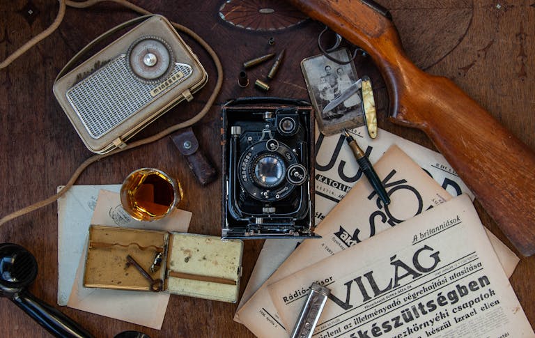 A collection of vintage items including a camera, radio, and newspaper creates an old-fashioned vibe.