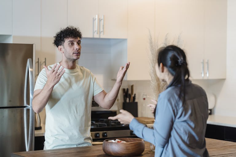 A couple in a tense conversation in a modern kitchen, expressing emotions.