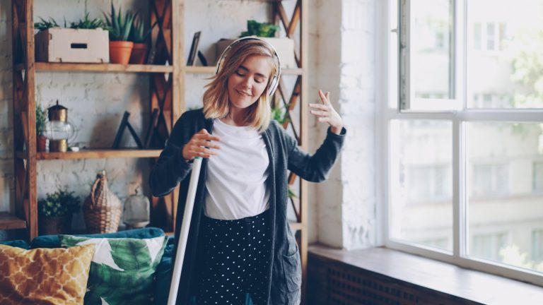 Woman listening to music while cleaning the room