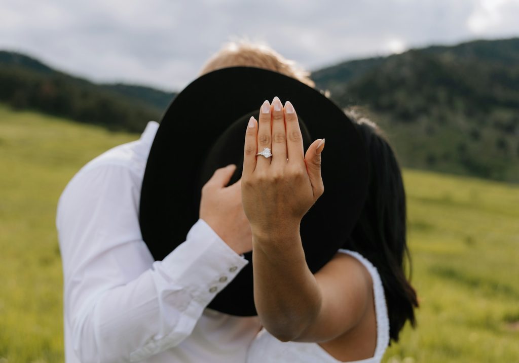 Couple showing engagement ring with hat