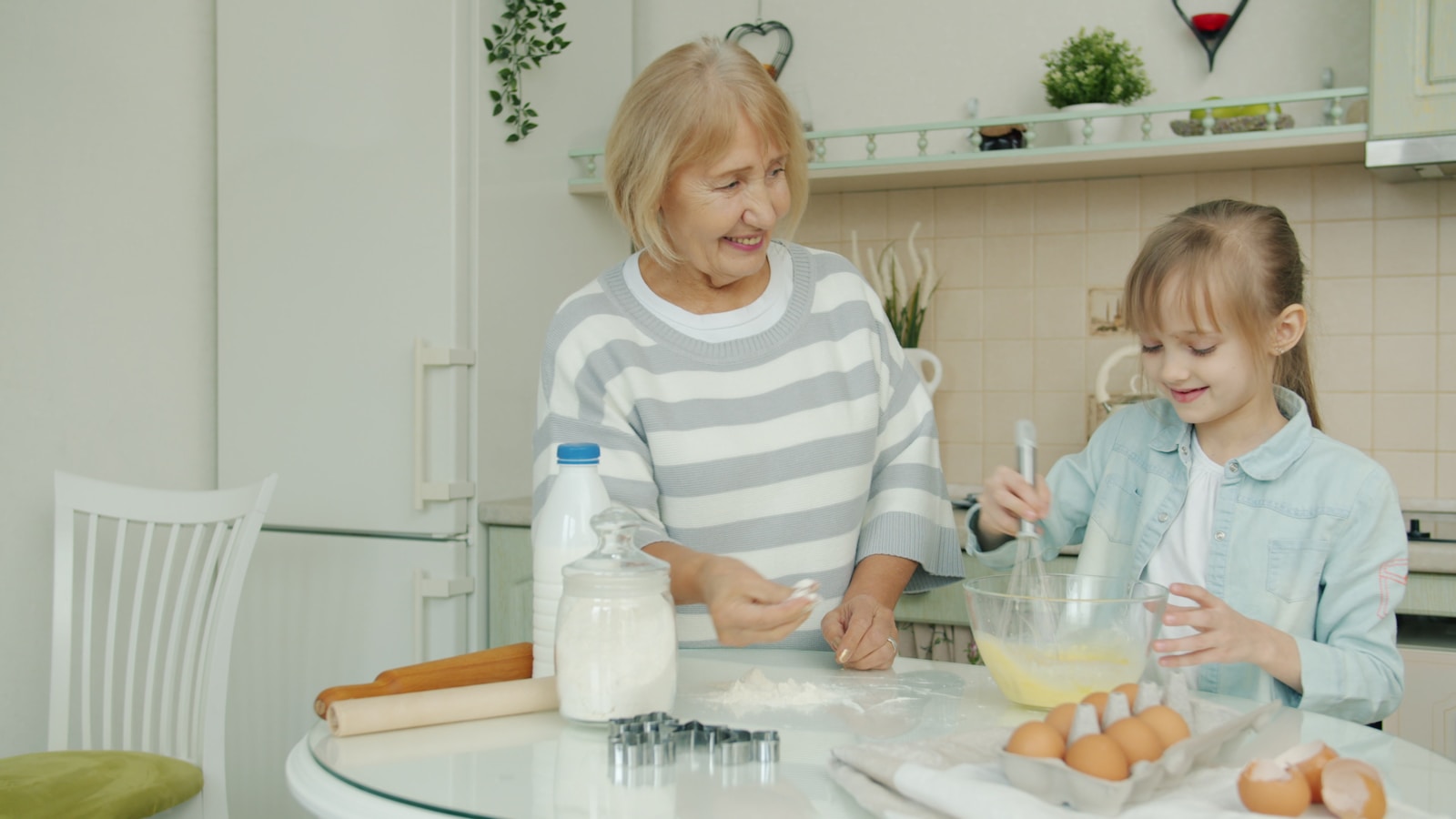 Grandmother and granddaughter baking together in the kitchen.