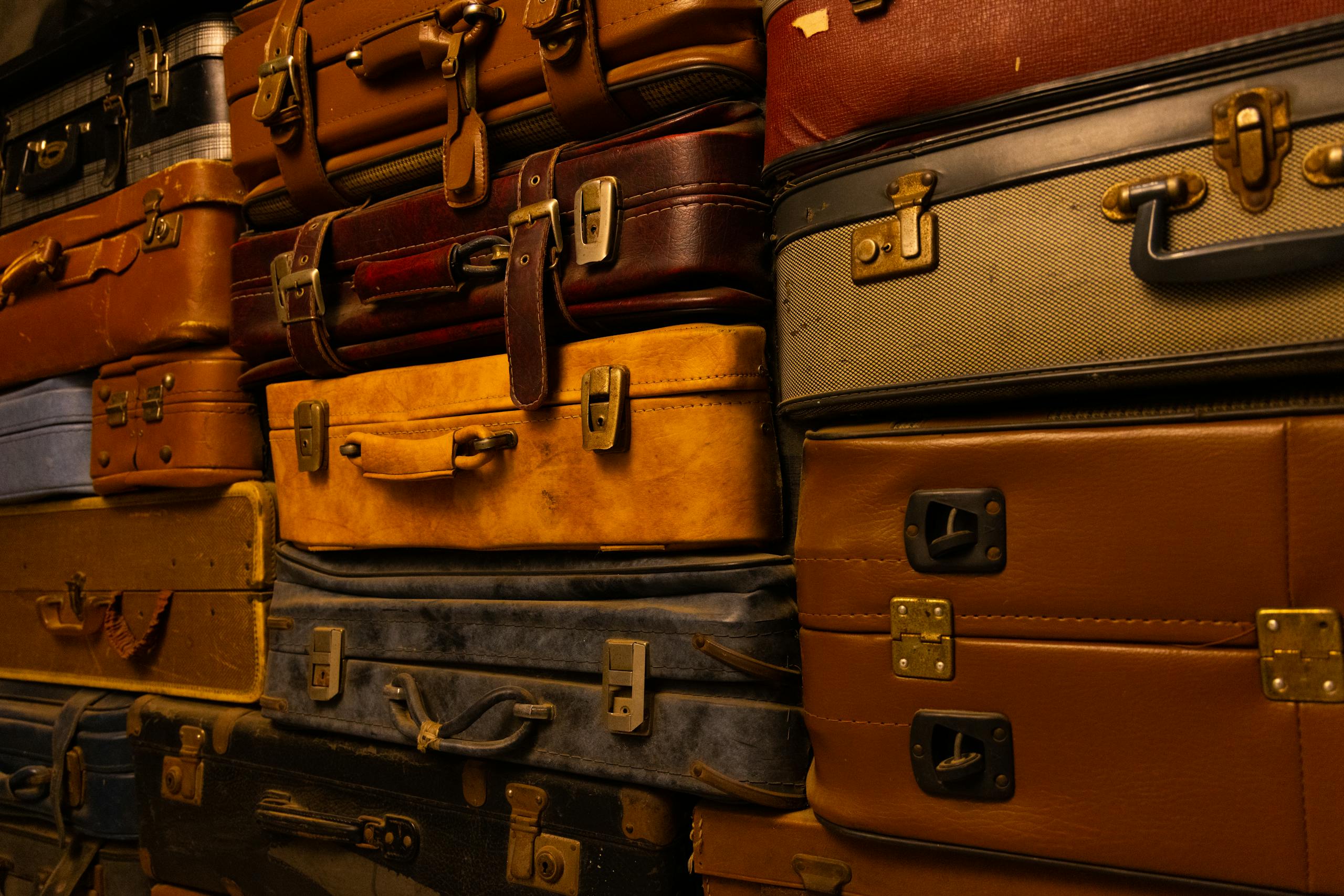 Stack of vintage suitcases showcasing assorted colors and textures in warm lighting.