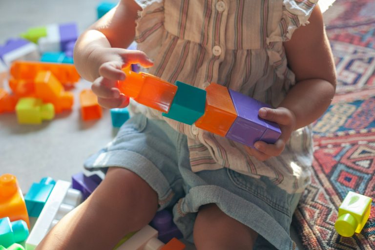 girl in brown button up shirt holding blue and orange plastic toy