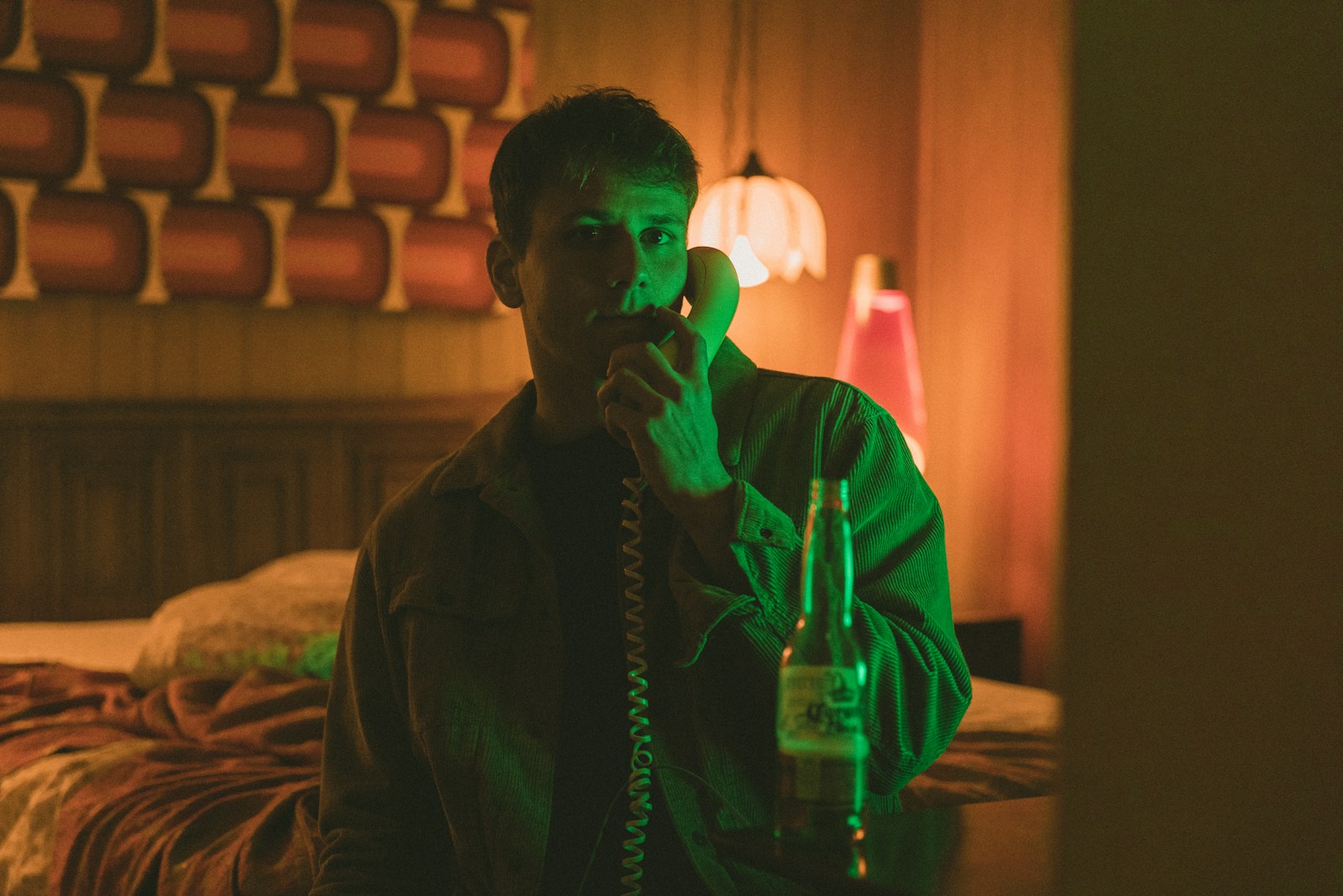 man in black jacket holding green telephone