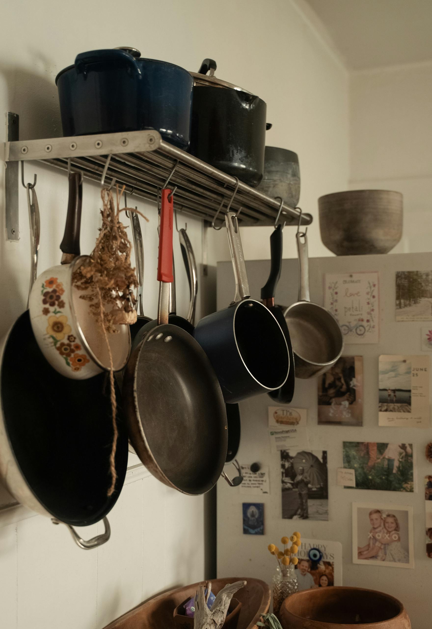 Vintage kitchen with hanging cookware and personal photos.