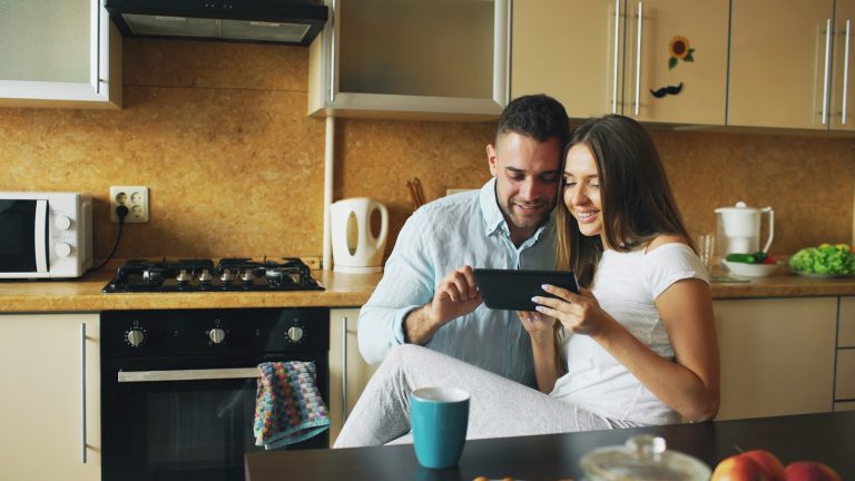 Couple looking at a tablet in a kitchen.