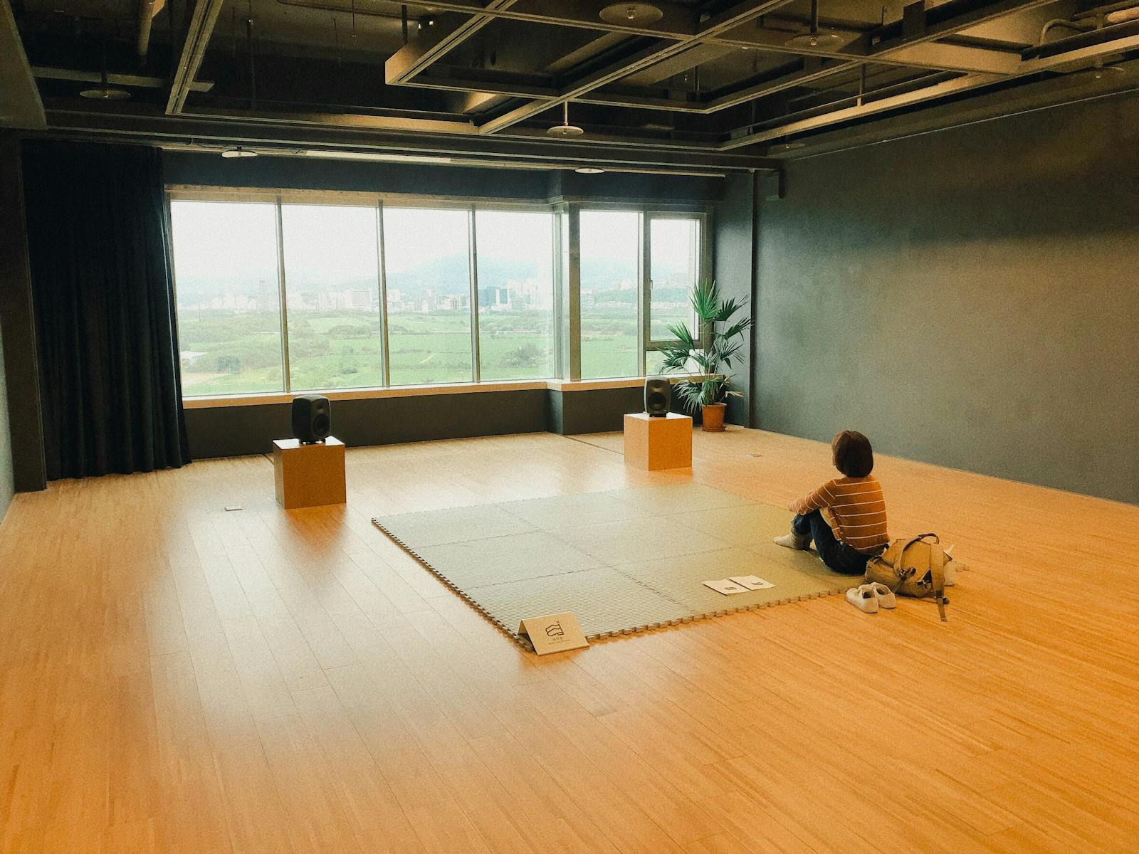 A person in a modern, empty room with large windows, emphasizing tranquility.