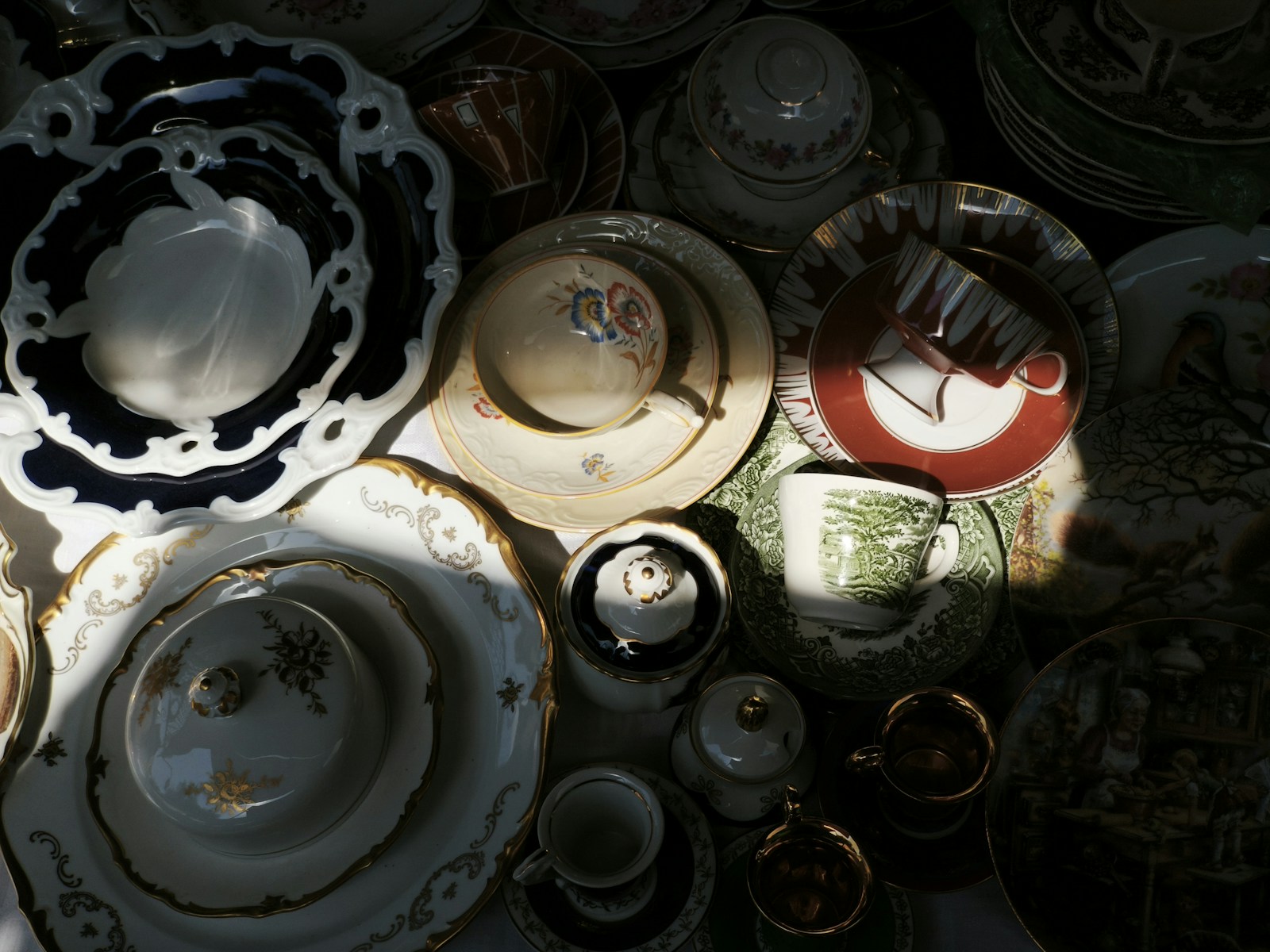 Antique dishes and teacups are arranged close together.