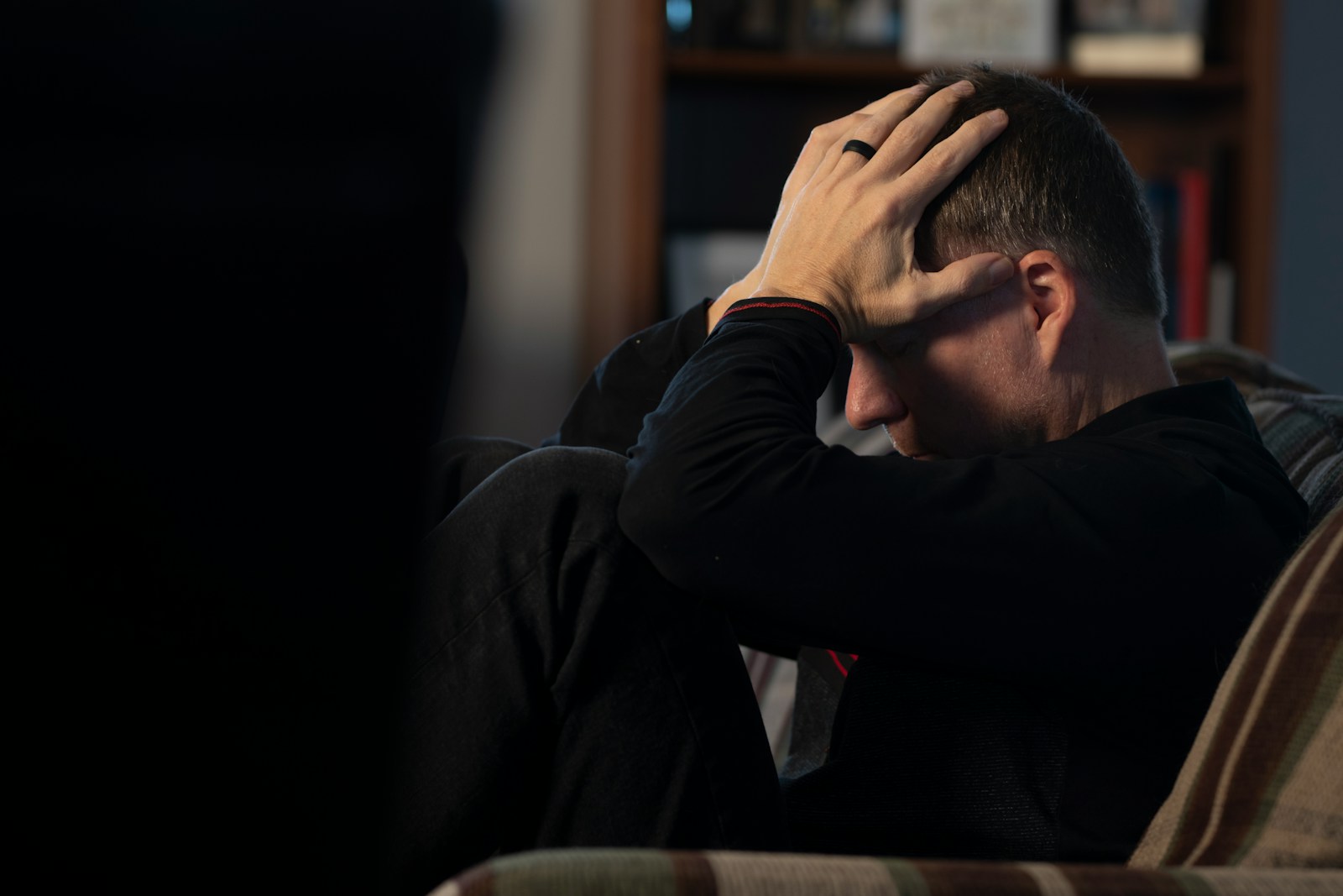 a man sitting on a couch holding his head in his hands