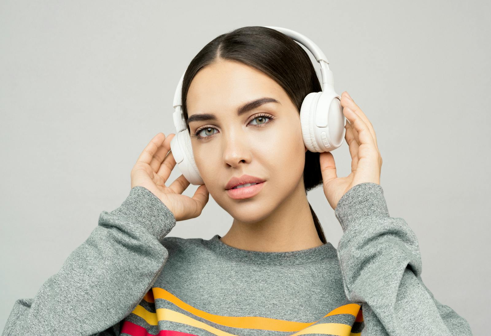 Portrait of a young woman wearing headphones, enjoying music indoors with a casual expression.