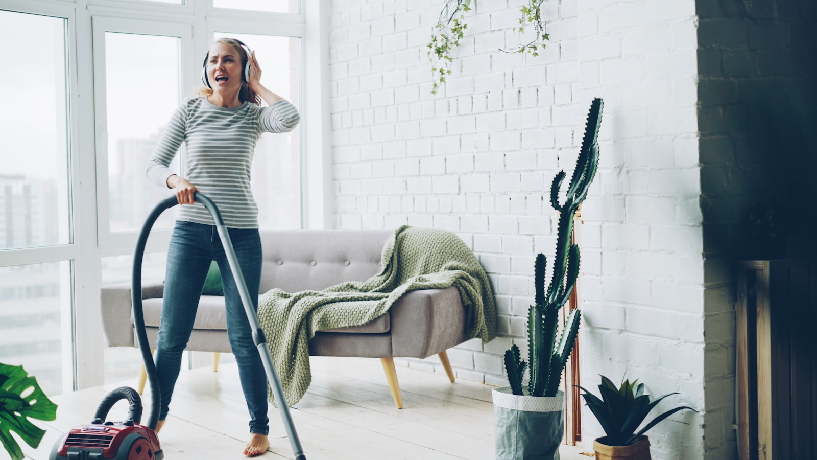Woman vacuuming and listening to music with headphones.