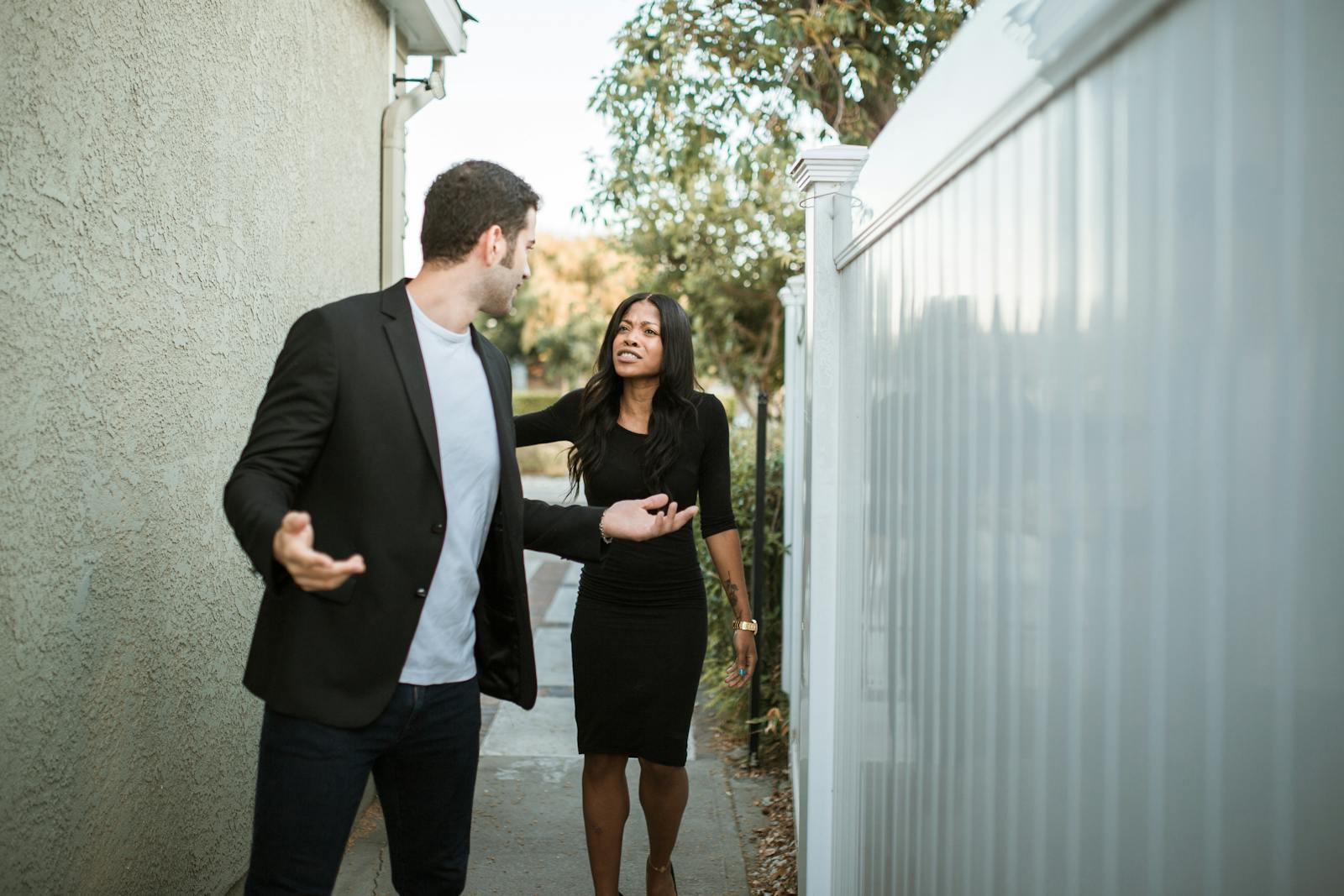A couple arguing in an outdoor narrow passageway, showcasing relationship tension.