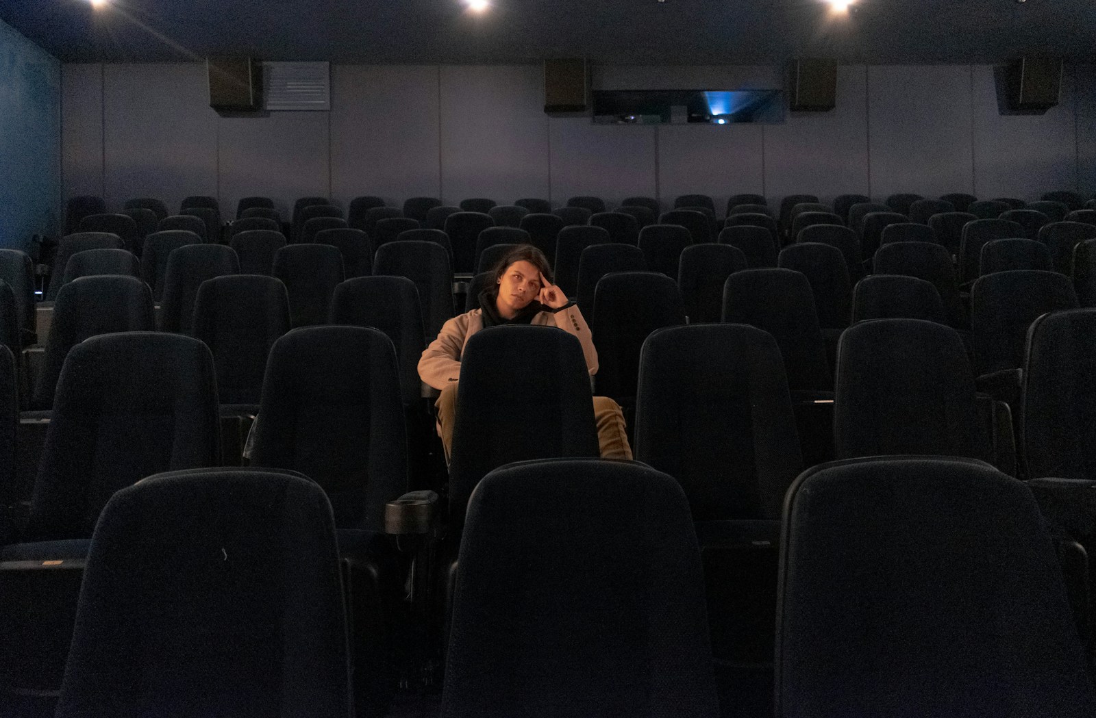 a man sitting in a movie theater talking on a cell phone
